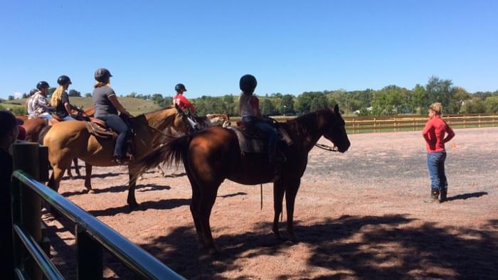 Teenagers mounted on horses at a group horse riding lesson.